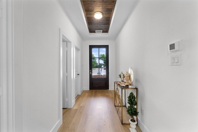 doorway to outside featuring light wood-type flooring, wood ceiling, and a tray ceiling