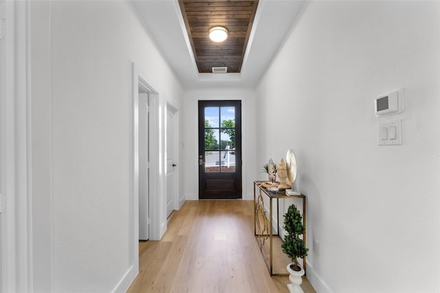 doorway with a raised ceiling, light hardwood / wood-style flooring, and wooden ceiling