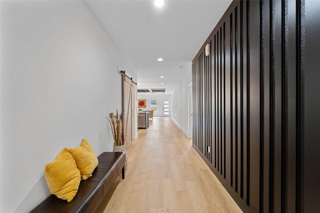 corridor featuring a barn door and light hardwood / wood-style flooring