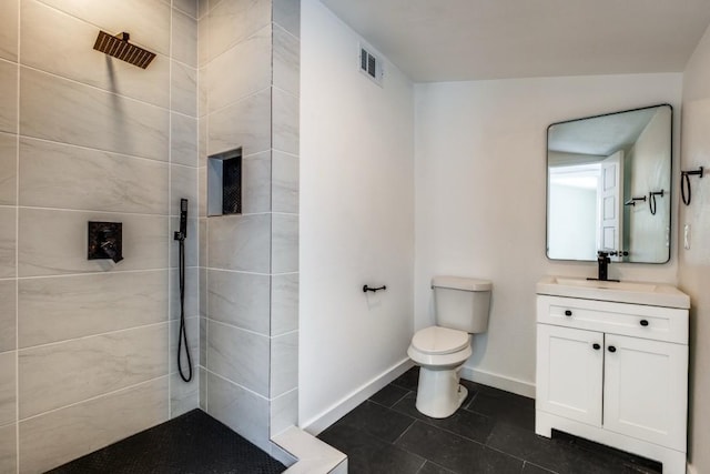 bathroom featuring vanity, lofted ceiling, tile patterned flooring, toilet, and tiled shower