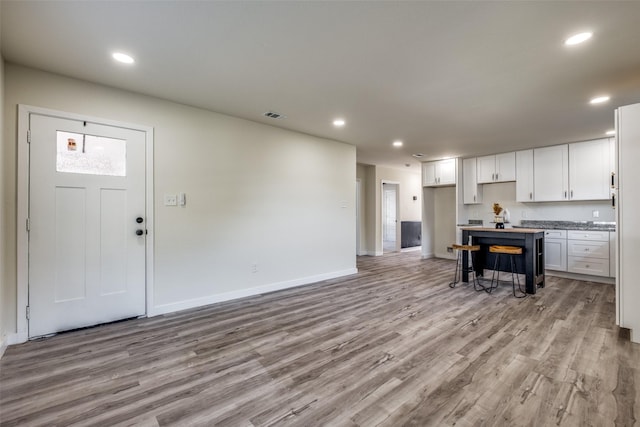 kitchen featuring white cabinets, a kitchen breakfast bar, and light hardwood / wood-style flooring