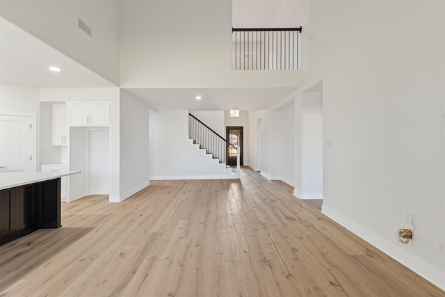 unfurnished living room with light hardwood / wood-style flooring and a high ceiling