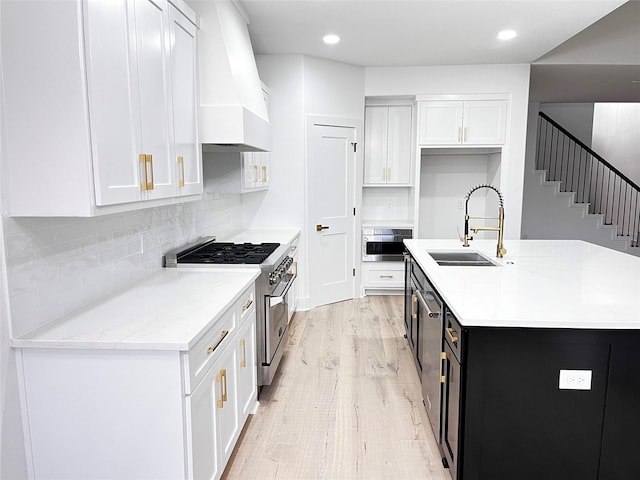 kitchen featuring appliances with stainless steel finishes, light hardwood / wood-style flooring, white cabinetry, and custom range hood