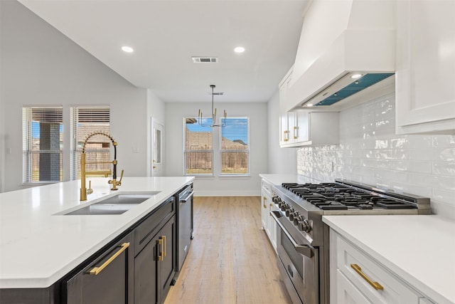 kitchen featuring custom range hood, stainless steel appliances, a kitchen island with sink, sink, and white cabinetry