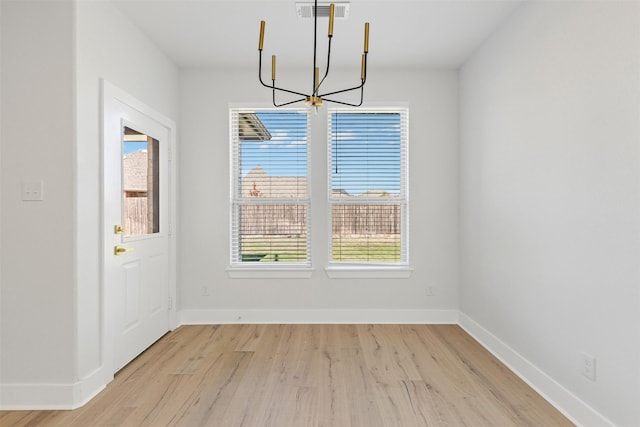 unfurnished dining area featuring an inviting chandelier and light wood-type flooring