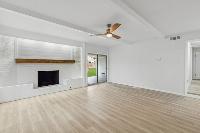 unfurnished living room with beamed ceiling, ceiling fan, light hardwood / wood-style floors, and a brick fireplace