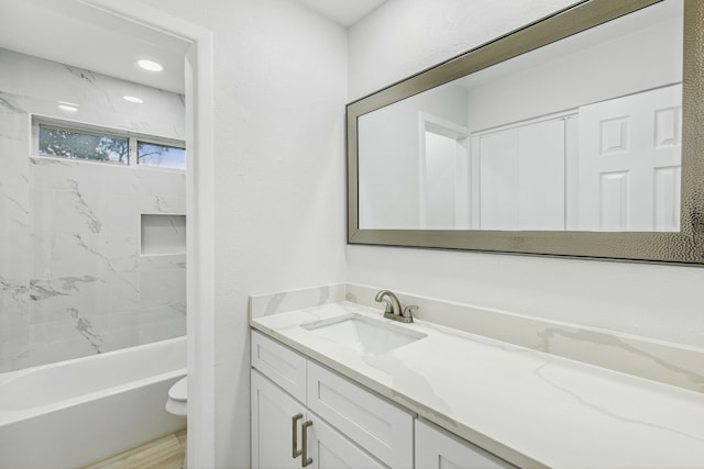 full bathroom featuring vanity, tiled shower / bath combo, and toilet