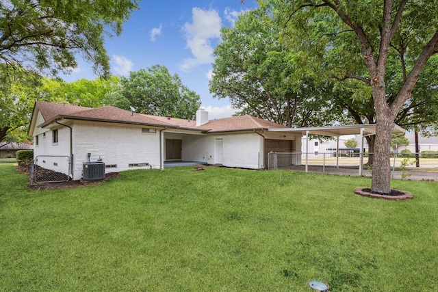 rear view of property with a carport, a yard, and central air condition unit