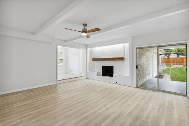 unfurnished living room featuring ceiling fan, beam ceiling, a brick fireplace, and light hardwood / wood-style flooring