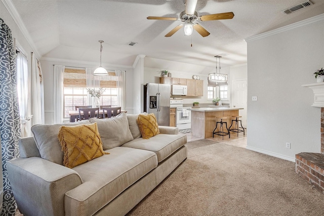 carpeted living room featuring ceiling fan, vaulted ceiling, ornamental molding, and a brick fireplace