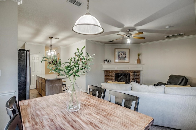 dining space with light tile patterned floors, a brick fireplace, ceiling fan, and ornamental molding