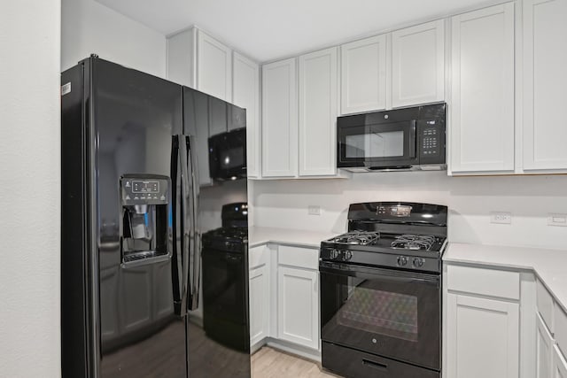 kitchen featuring black appliances, white cabinets, and light wood-type flooring