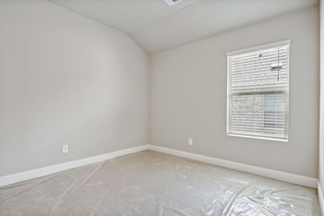 carpeted spare room with lofted ceiling