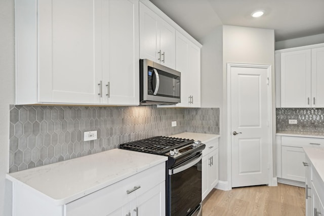 kitchen featuring decorative backsplash, appliances with stainless steel finishes, light wood-type flooring, light stone counters, and white cabinetry