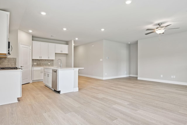 kitchen with light wood-type flooring, a center island with sink, white cabinetry, and stainless steel appliances