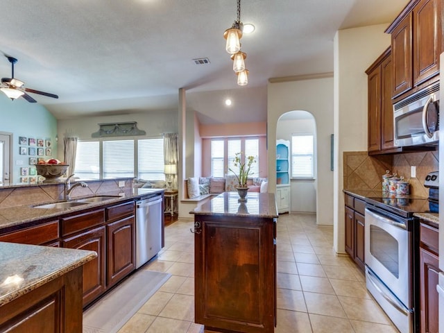 kitchen featuring sink, decorative backsplash, light tile patterned floors, a kitchen island, and stainless steel appliances