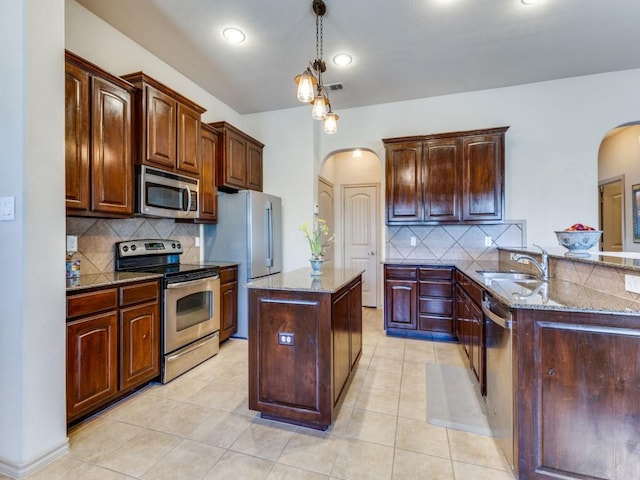 kitchen with sink, stainless steel appliances, light stone counters, backsplash, and kitchen peninsula