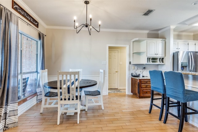 dining room featuring light hardwood / wood-style flooring, crown molding, and a notable chandelier