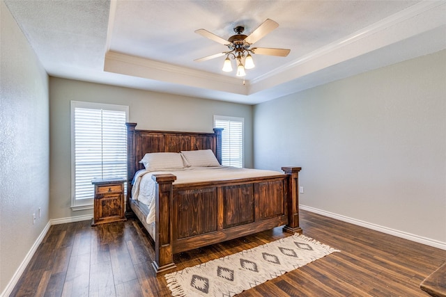 bedroom with dark hardwood / wood-style floors, crown molding, ceiling fan, and a tray ceiling