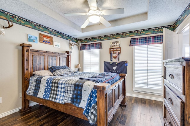 bedroom featuring ceiling fan, dark hardwood / wood-style floors, a raised ceiling, and a textured ceiling