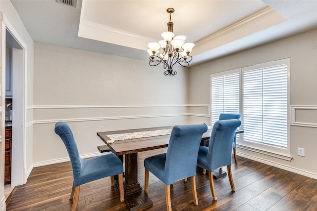 dining room featuring dark hardwood / wood-style flooring, a raised ceiling, crown molding, and a chandelier