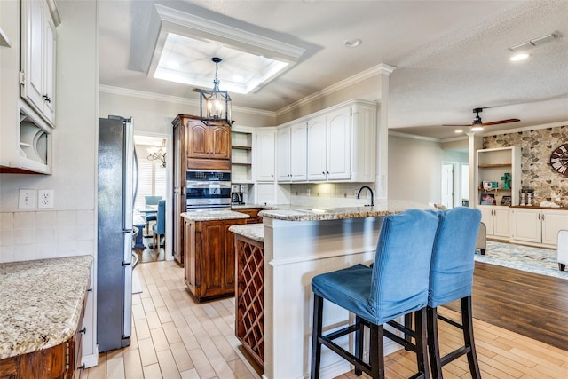 kitchen featuring white cabinets, light hardwood / wood-style floors, a kitchen bar, kitchen peninsula, and stainless steel appliances