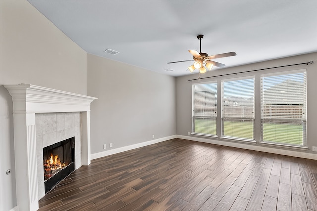 unfurnished living room with a tile fireplace, dark hardwood / wood-style floors, a wealth of natural light, and ceiling fan