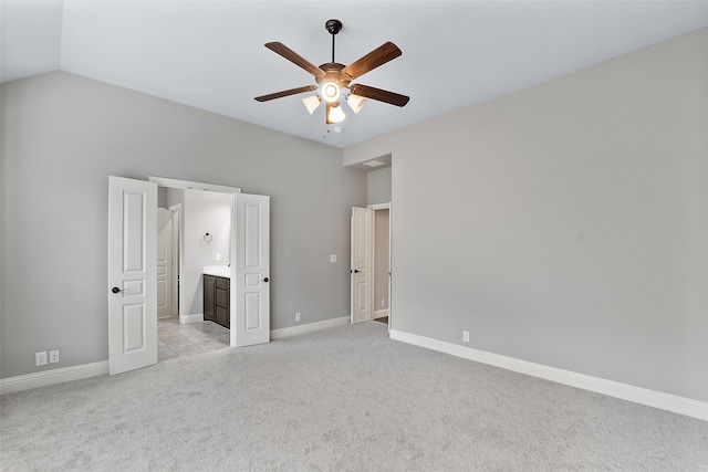 unfurnished bedroom with ensuite bath, ceiling fan, light colored carpet, and lofted ceiling