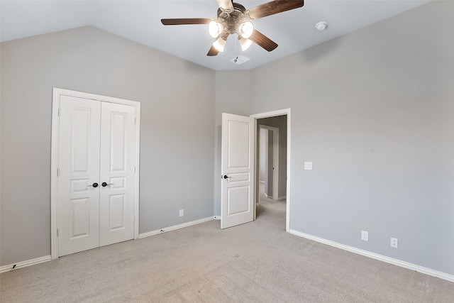 unfurnished bedroom featuring ceiling fan, a closet, light colored carpet, and vaulted ceiling