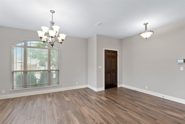 empty room with dark hardwood / wood-style flooring and a notable chandelier