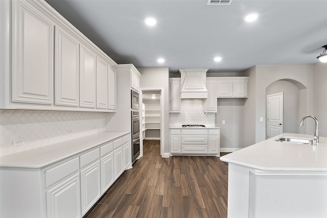 kitchen with custom exhaust hood, sink, dark hardwood / wood-style floors, white cabinetry, and stainless steel microwave