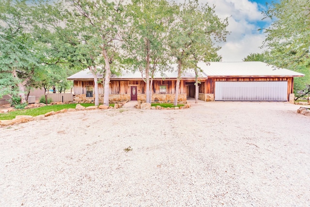 ranch-style home with stone siding, an attached garage, an outdoor structure, and driveway