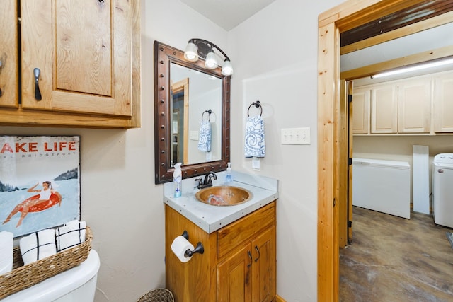 bathroom with vanity, washer / dryer, concrete floors, and toilet