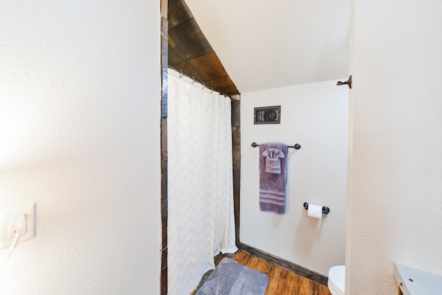 bathroom featuring walk in shower, toilet, lofted ceiling, and hardwood / wood-style flooring