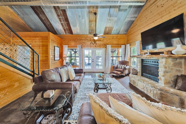 living room with a stone fireplace, ceiling fan, and wooden walls