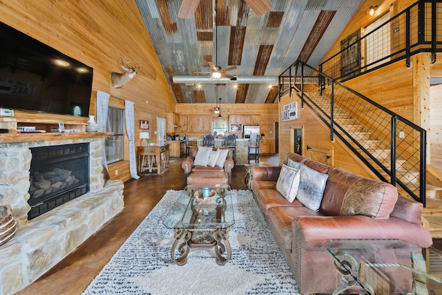 living room with high vaulted ceiling, wooden walls, and a stone fireplace