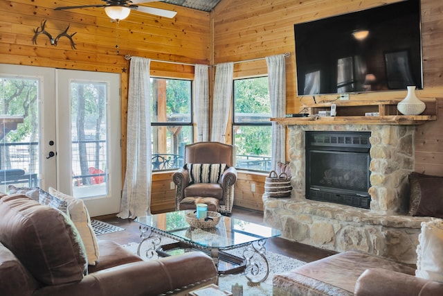 living room featuring vaulted ceiling, a wealth of natural light, a fireplace, and wood walls