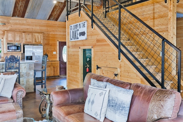 living room featuring wooden walls, beam ceiling, high vaulted ceiling, and concrete floors