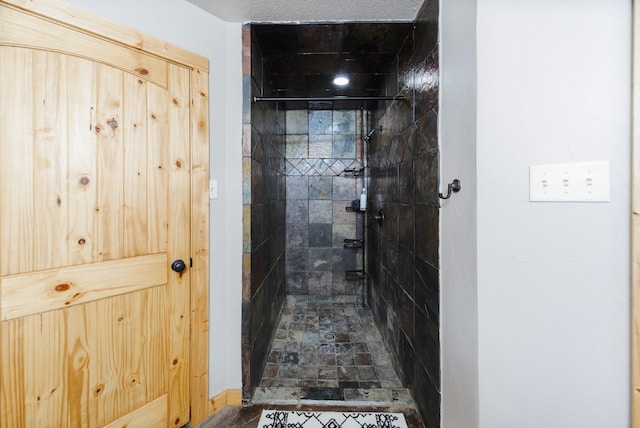 bathroom with a textured ceiling and tiled shower