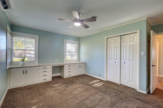 unfurnished office with ceiling fan, dark carpet, and crown molding