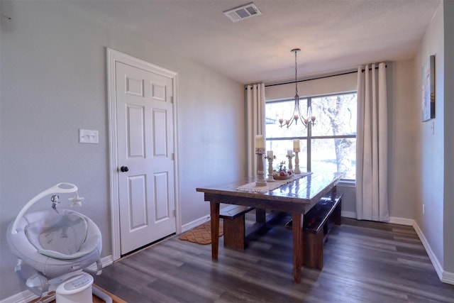 dining space featuring dark wood-type flooring and a notable chandelier