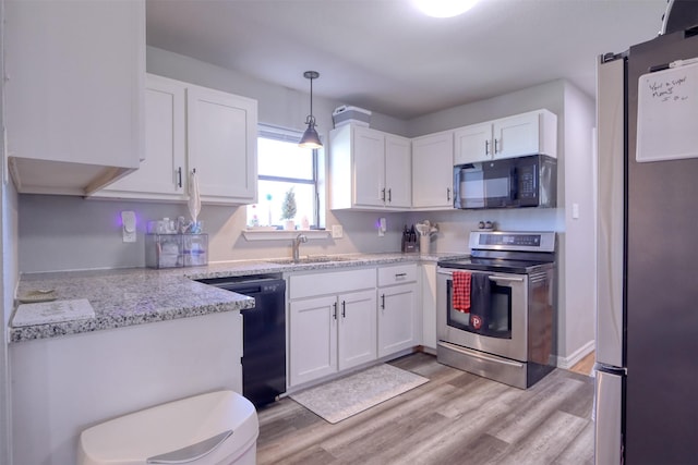 kitchen with light wood-type flooring, sink, black appliances, white cabinets, and hanging light fixtures