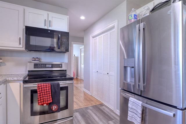 kitchen with light hardwood / wood-style flooring, white cabinets, and stainless steel appliances