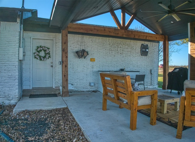 view of exterior entry with ceiling fan and a patio