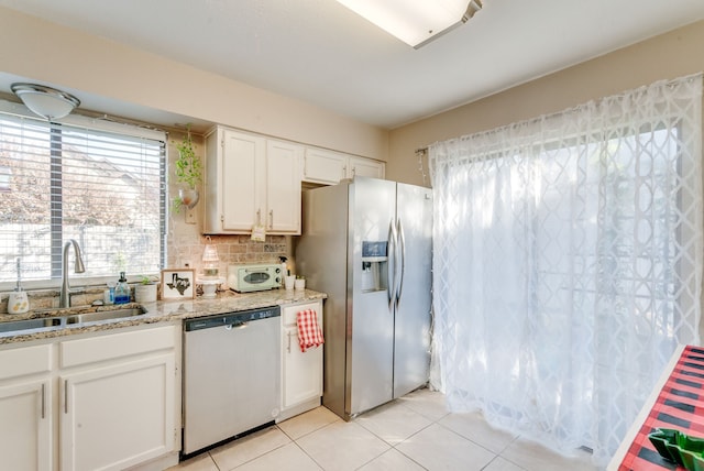 kitchen featuring light tile patterned flooring, appliances with stainless steel finishes, tasteful backsplash, white cabinetry, and sink