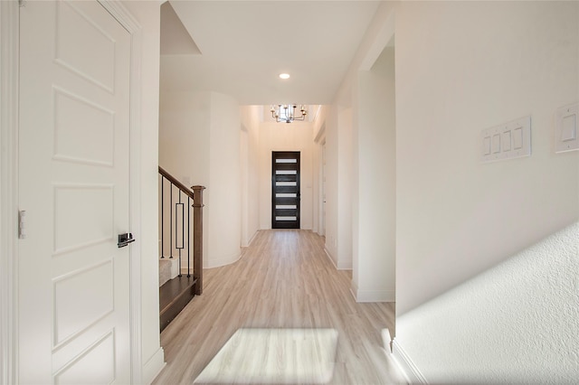 hallway with an inviting chandelier and light hardwood / wood-style floors