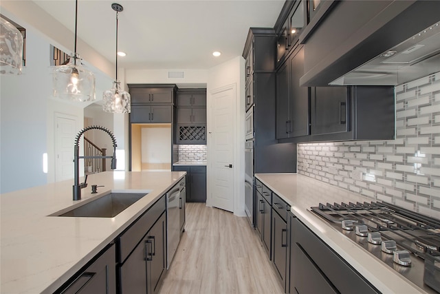 kitchen featuring sink, custom exhaust hood, hanging light fixtures, appliances with stainless steel finishes, and light stone countertops