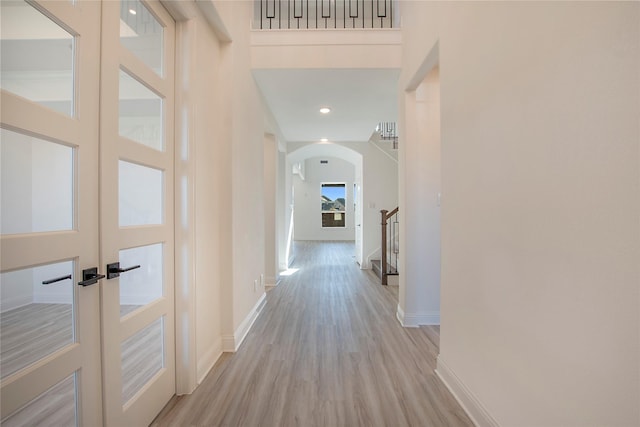 hall with a high ceiling and light wood-type flooring