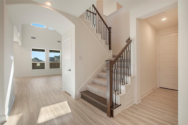 staircase with a towering ceiling and wood-type flooring