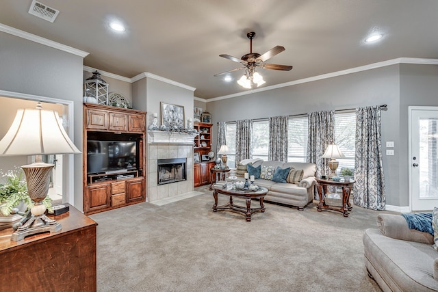 carpeted living room featuring crown molding, a tile fireplace, and ceiling fan